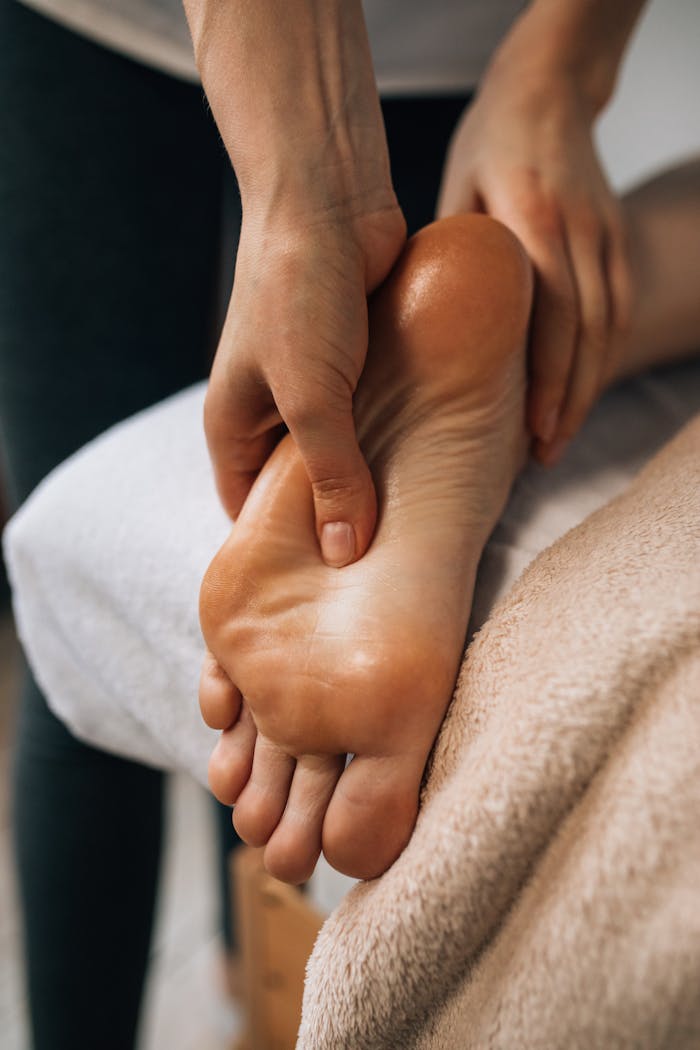 who-we-are Hands massaging a foot to provide relaxation and promote wellness indoors.